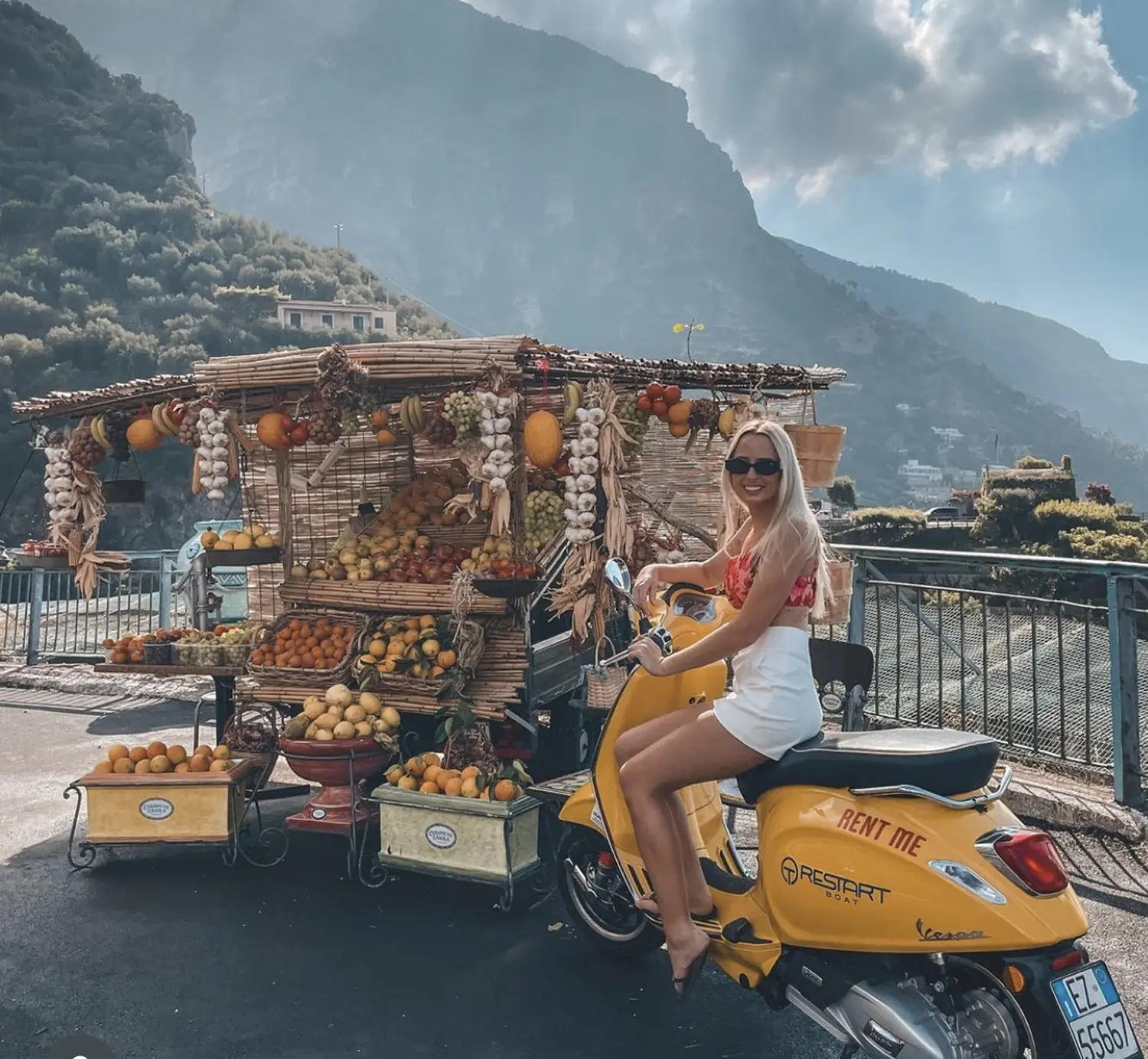Woman riding a Vespa with Positano in the background